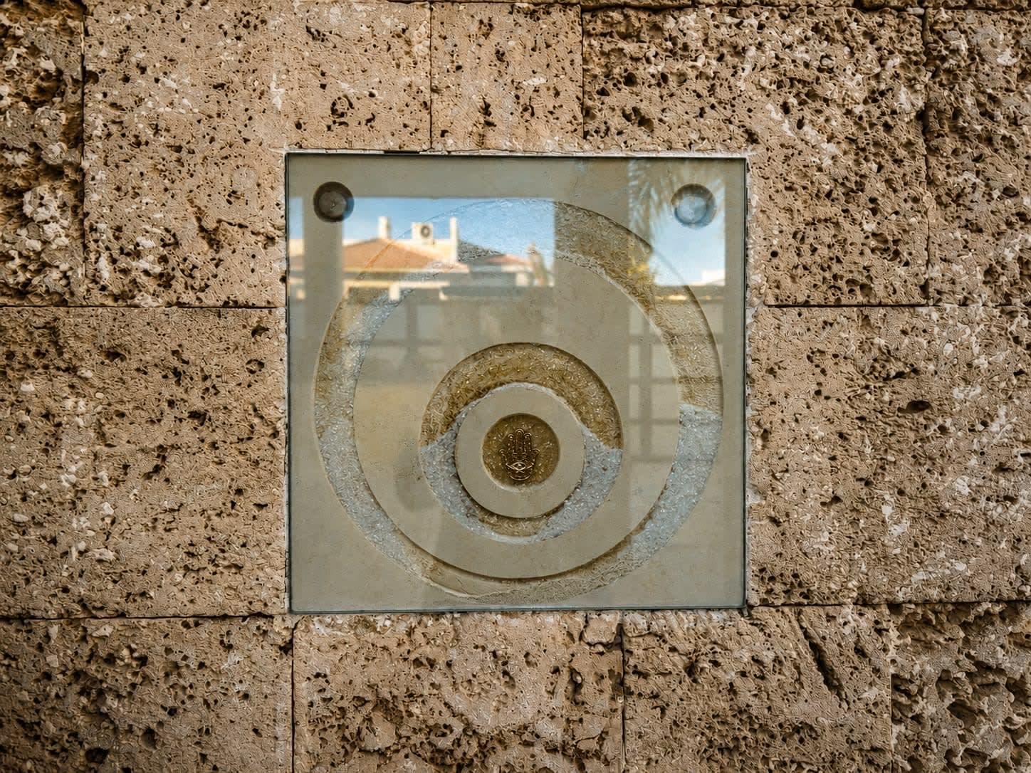 חוץ, קיר אבן עם אלמנט עיצובי מרובע ובו עיגולים, וילה באילת.
